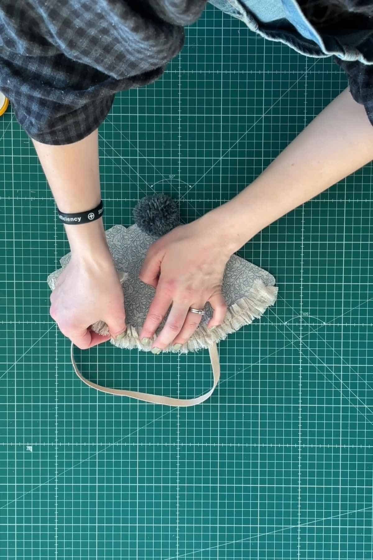 A person glues a piece of ruffled trim to the edge of a party hat.
