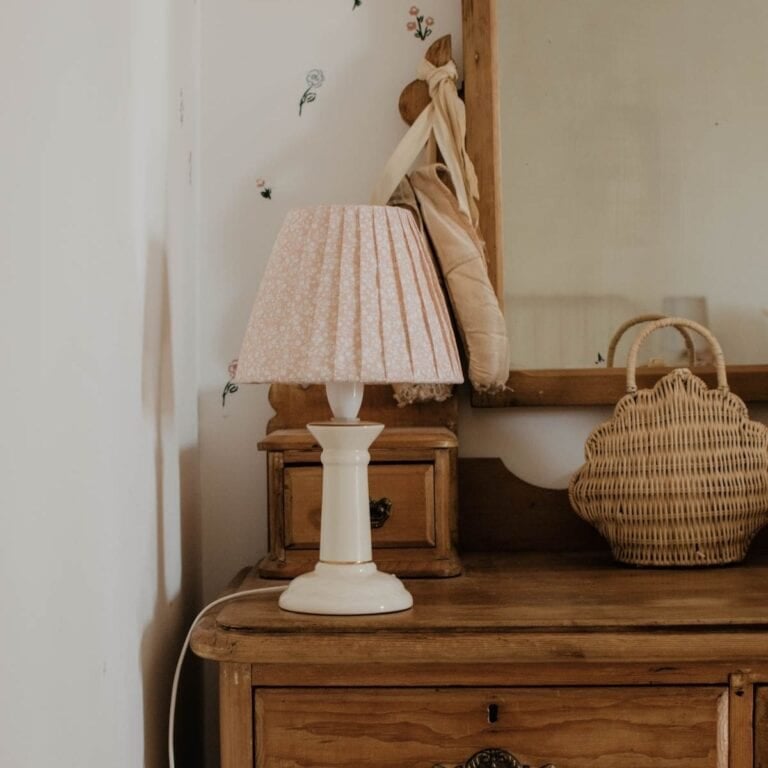 A lamp with an upcycled DIY pleated lampshade sits on an antique dresser