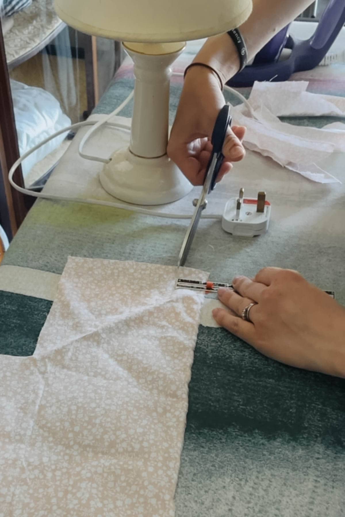 A person cuts a piece of fabric into 4cm strips using a pair of fabric scissors