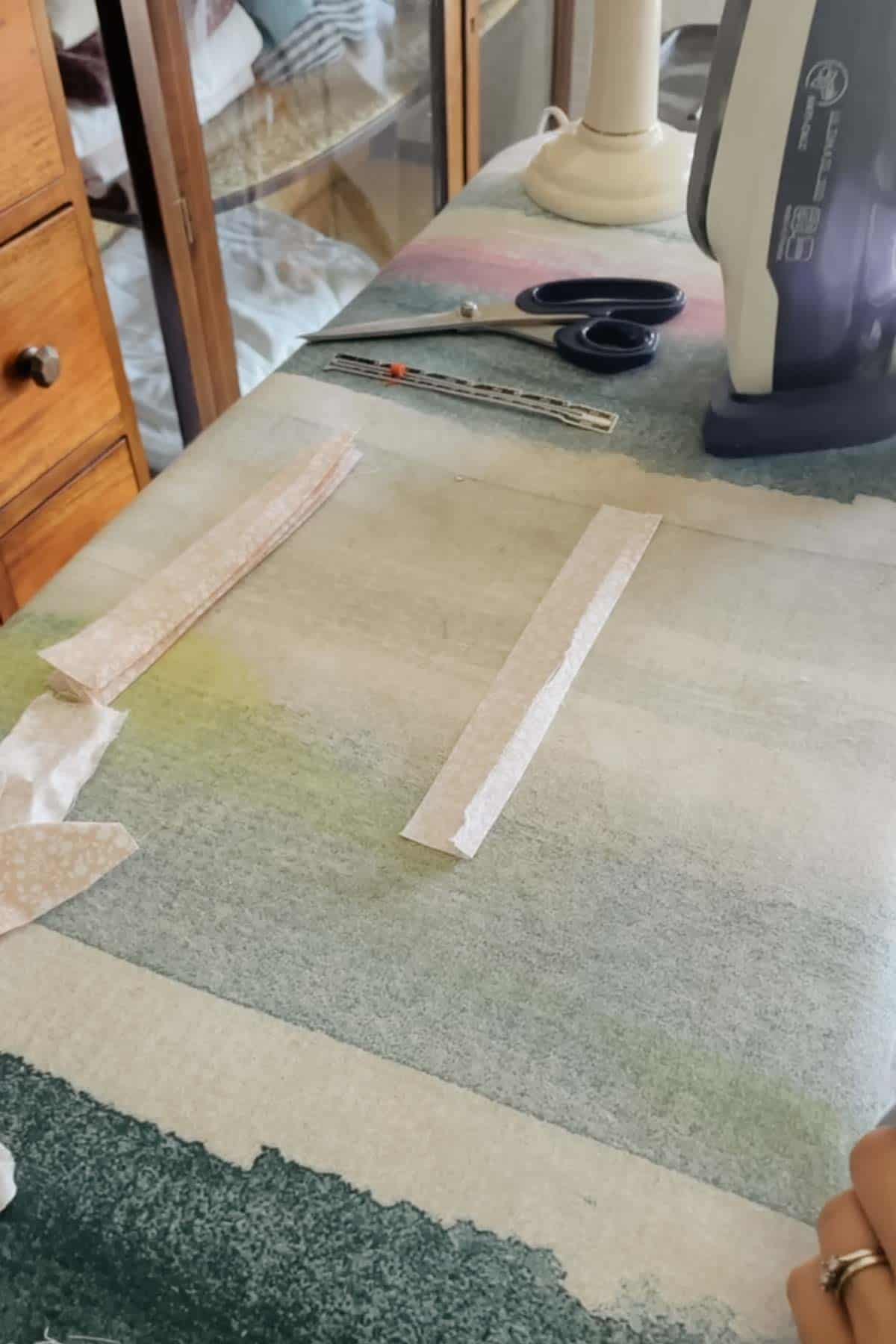 A strip of pink floral fabric with one long side folded in and pressed by half a centimetre