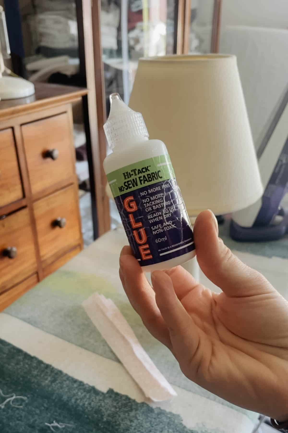 a person holds up a bottle of impex tacky fabric glue