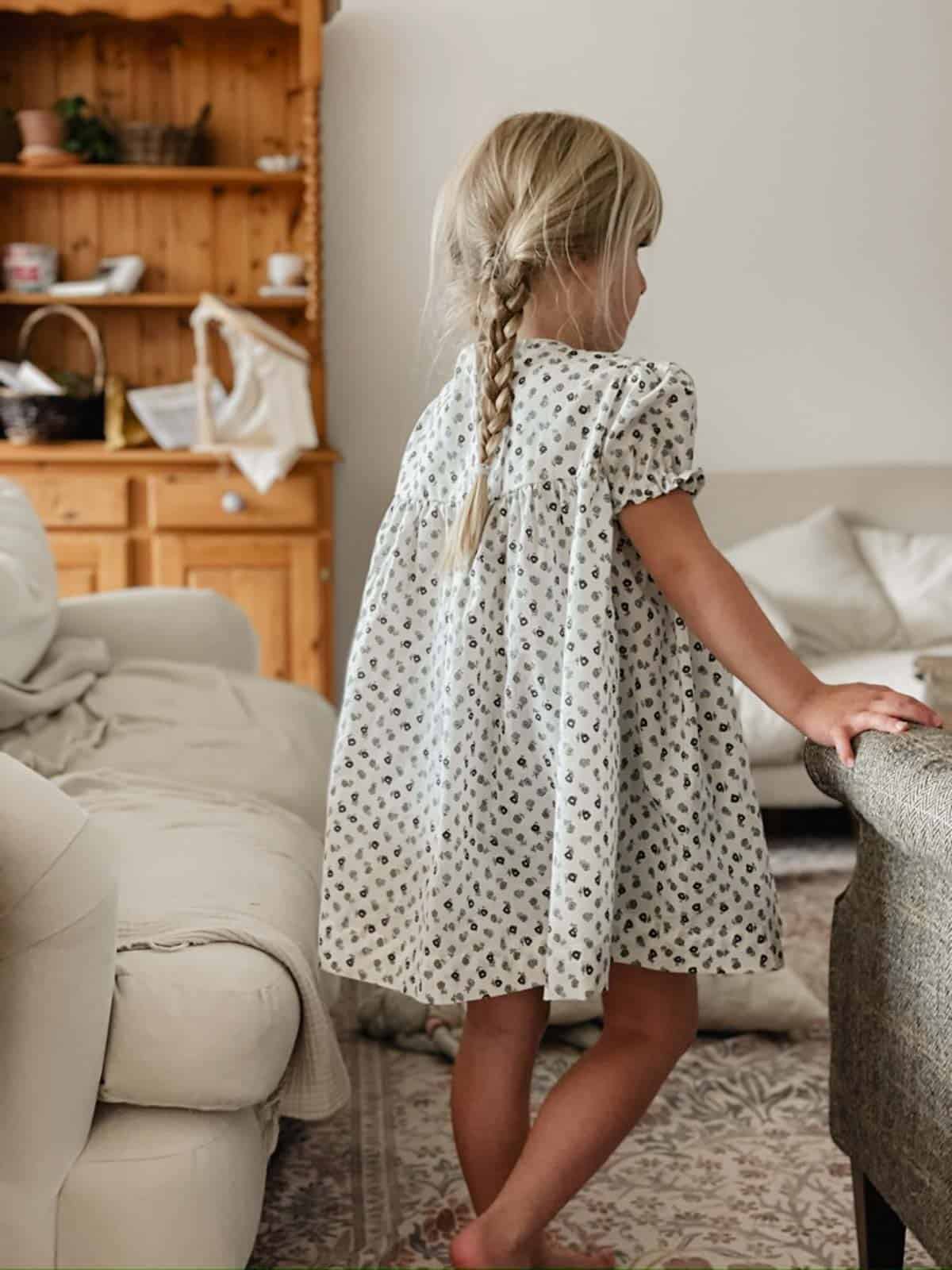 A little girl wears a blue and green handmade floral dress