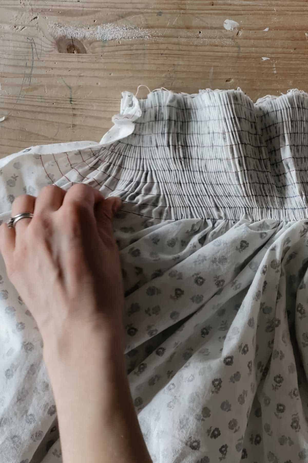 A person gathers fabric into even pleats