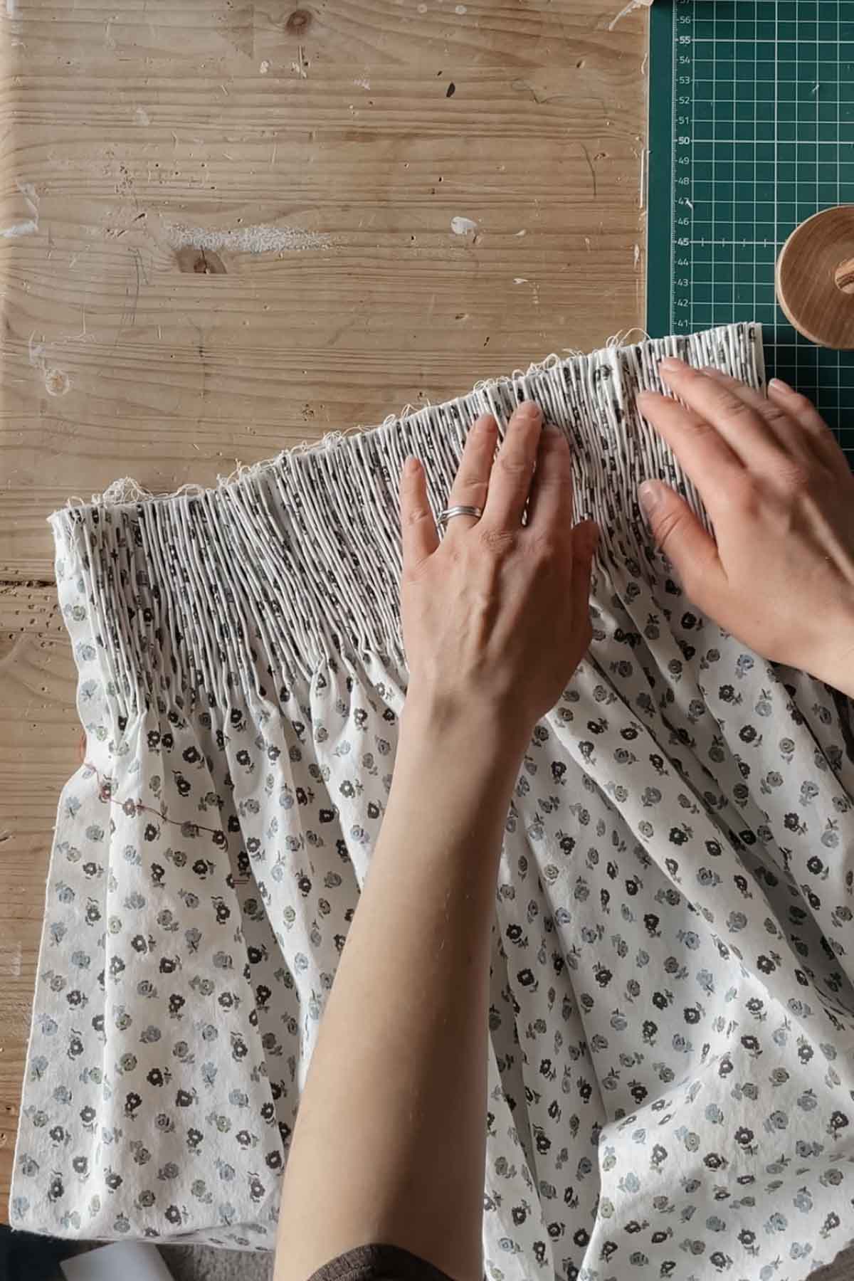 A person adjust the tiny pleats to prepare them for smocking