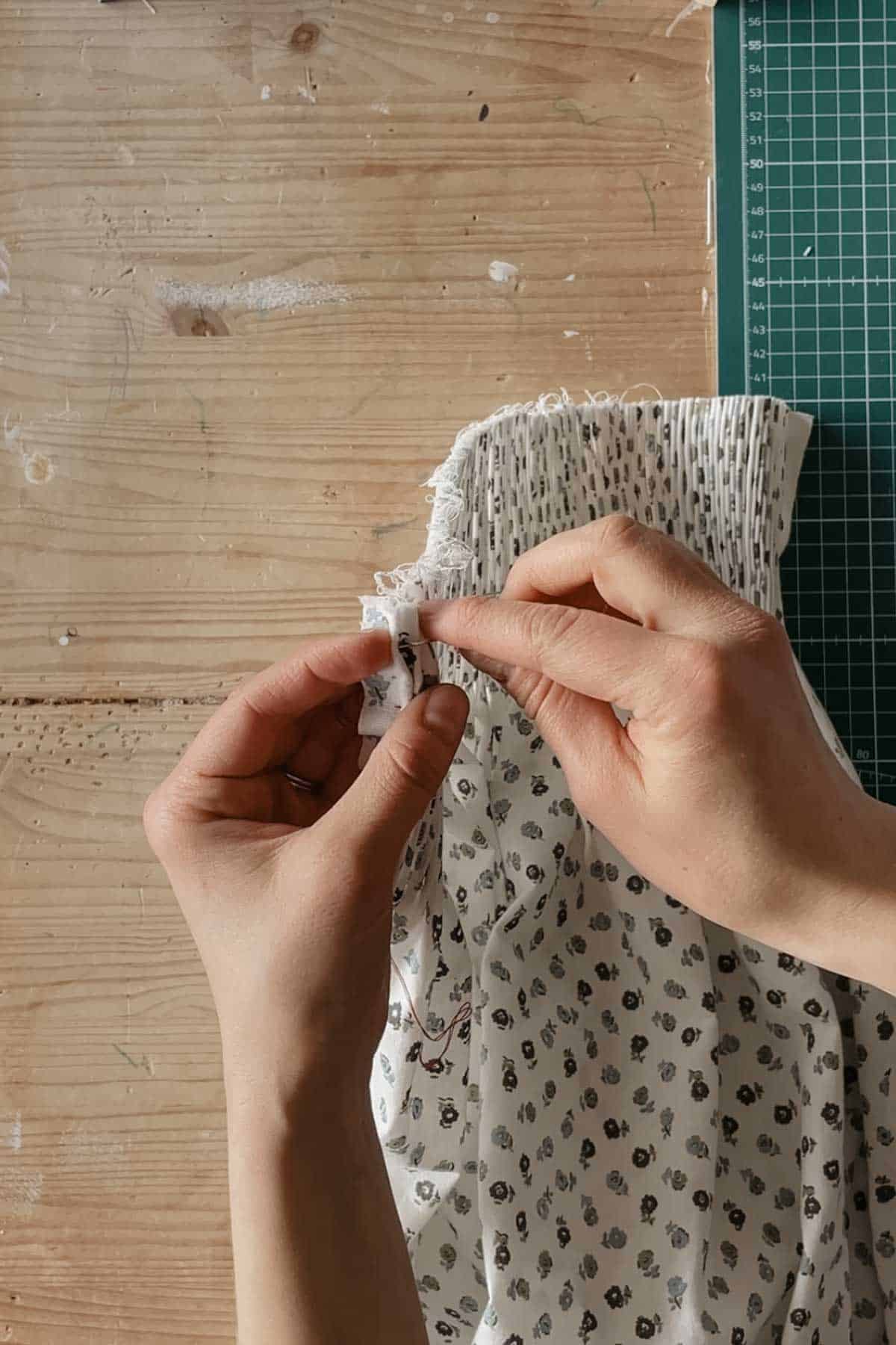 A person stitches through the first pleat