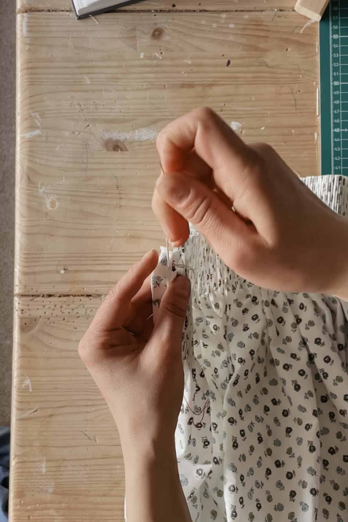 A person stitches through the first pleat