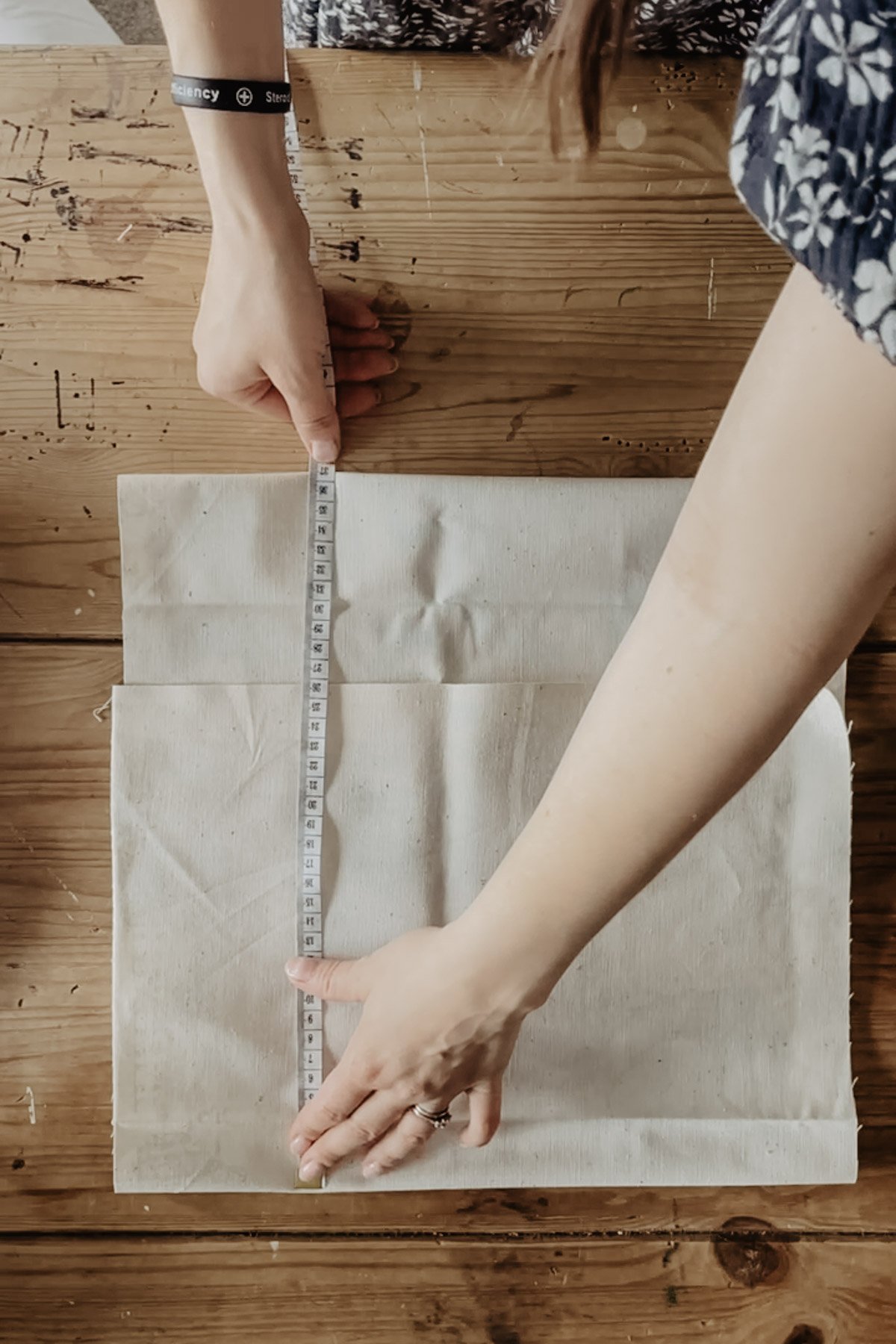 The folded cushion cover is measured with a tape measure.