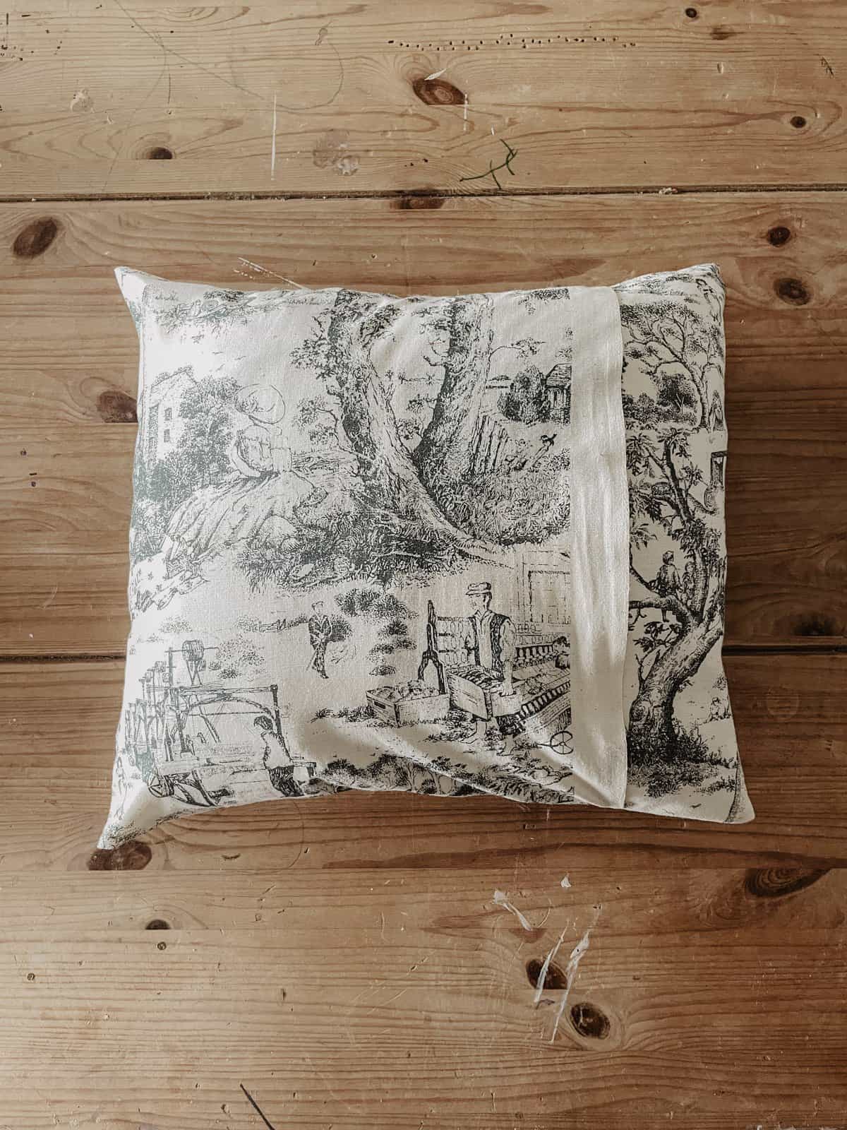 The back of an envelope pillow cover in a toile fabric.