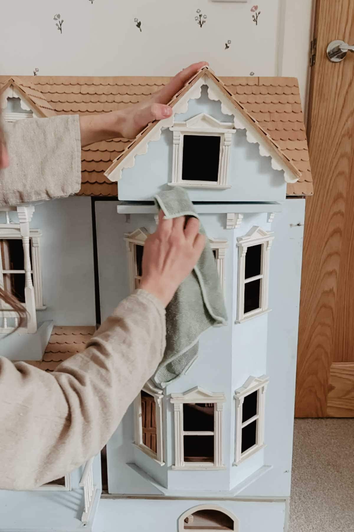 A lady wipes the dollhouse clean.
