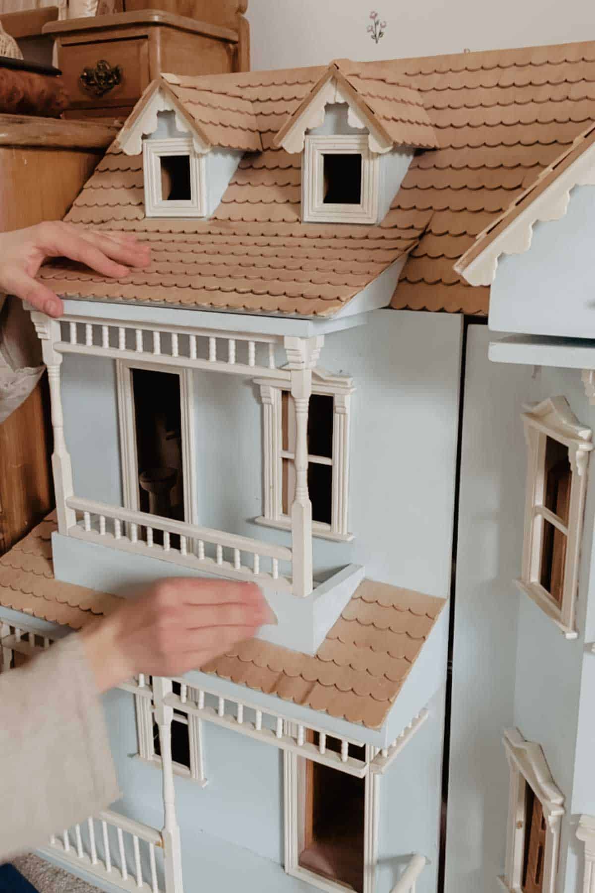 A lady sands a blue dollhouse ready for painting. 
