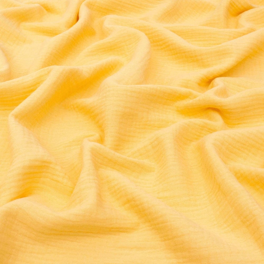 Soft, yellow fabric with a crinkled, textured surface and gentle folds throughout, creating a warm and cosy appearance—perfect for learning how to make a bed canopy for your room.