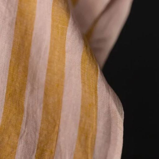 A close-up of fabric with vertical mustard yellow and light pink stripes, showing the texture and weave—perfect for discovering sewing tricks to sew faster and enhance your projects.