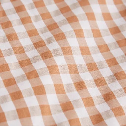 Close-up of fabric with a chequered pattern in beige and white, creating alternating squares in a grid-like design. Perfect for those looking to sew faster using clever sewing tricks, the fabric appears soft and slightly creased.