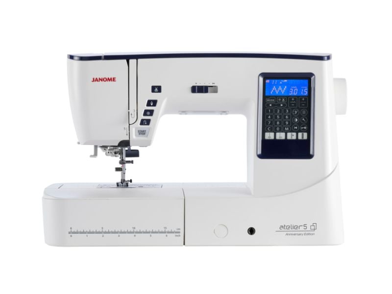 A modern Janome sewing machine with a digital display, numerous buttons, and a measurement guide on the base—perfect for those who want to sew faster. The machine is mostly white with navy blue accents.