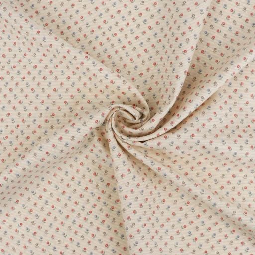 A close-up of beige fabric with a small red and grey floral dotted pattern, gathered at the centre in a gentle swirl—perfect for a beginner sewing project like a scrunchie or to follow along in a sewing tutorial.
